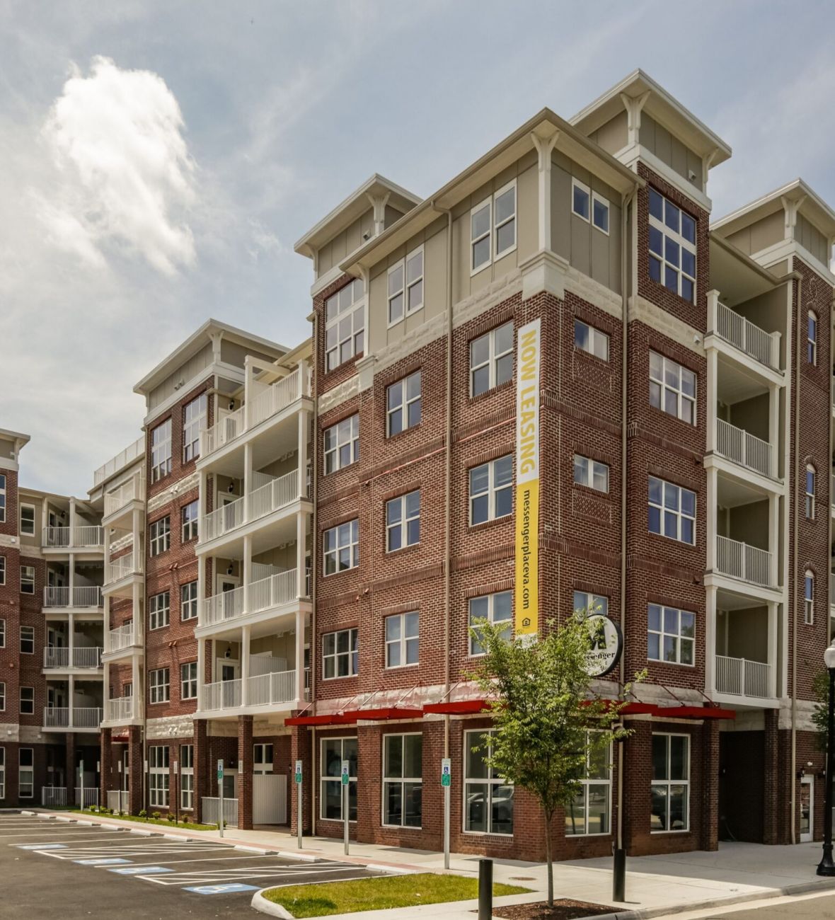 Attain on 5th apartment homes with Modern four-story brick apartment building with balconies and large windows, under a partly cloudy sky.