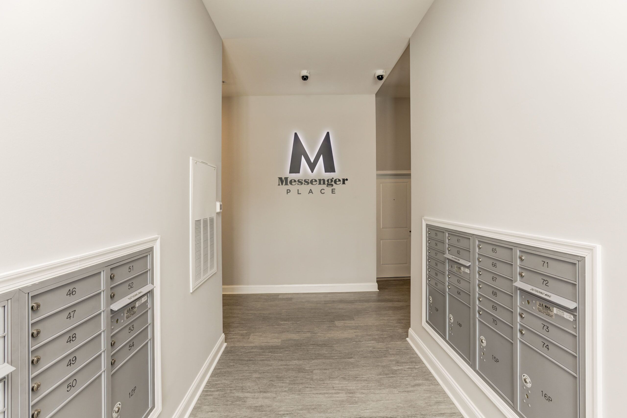Attain on 5th apartment homes with Hallway with gray mailboxes on both sides and a "Messenger Place" sign on the wall at the end.
