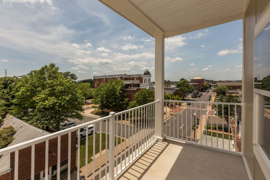 Attain on 5th apartment homes with View from a balcony overlooking a small town street, buildings, trees, and a partly cloudy sky.